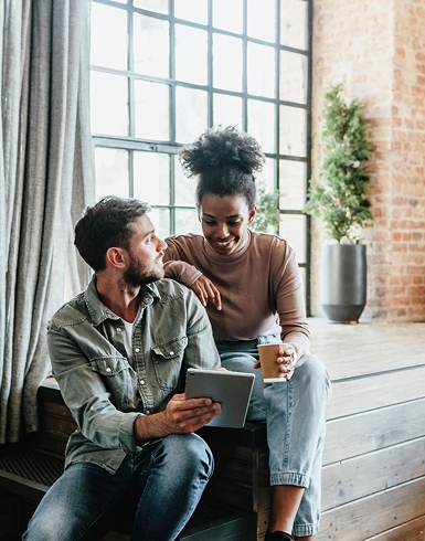 A couple sitting together looking at a laptop, planning their home purchase