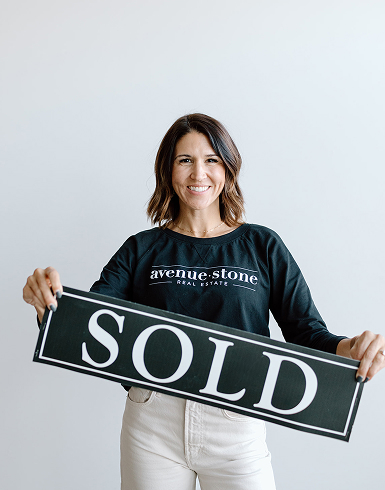 Real estate agent holding a SOLD sign, representing successful home transactions
